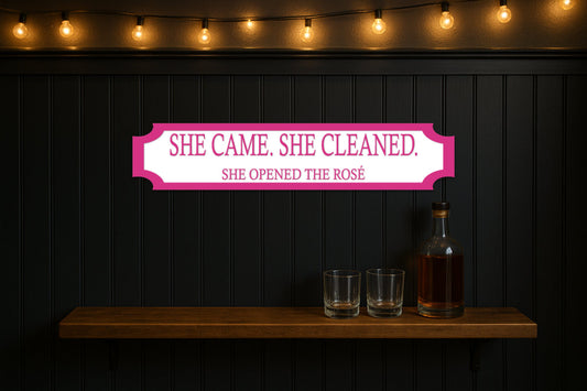 SHE CAME. SHE CLEANED. · SHE OPENED THE ROSÉ — personalised 3D street sign, shown in place