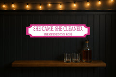SHE CAME. SHE CLEANED. · SHE OPENED THE ROSÉ — personalised 3D street sign, shown in place